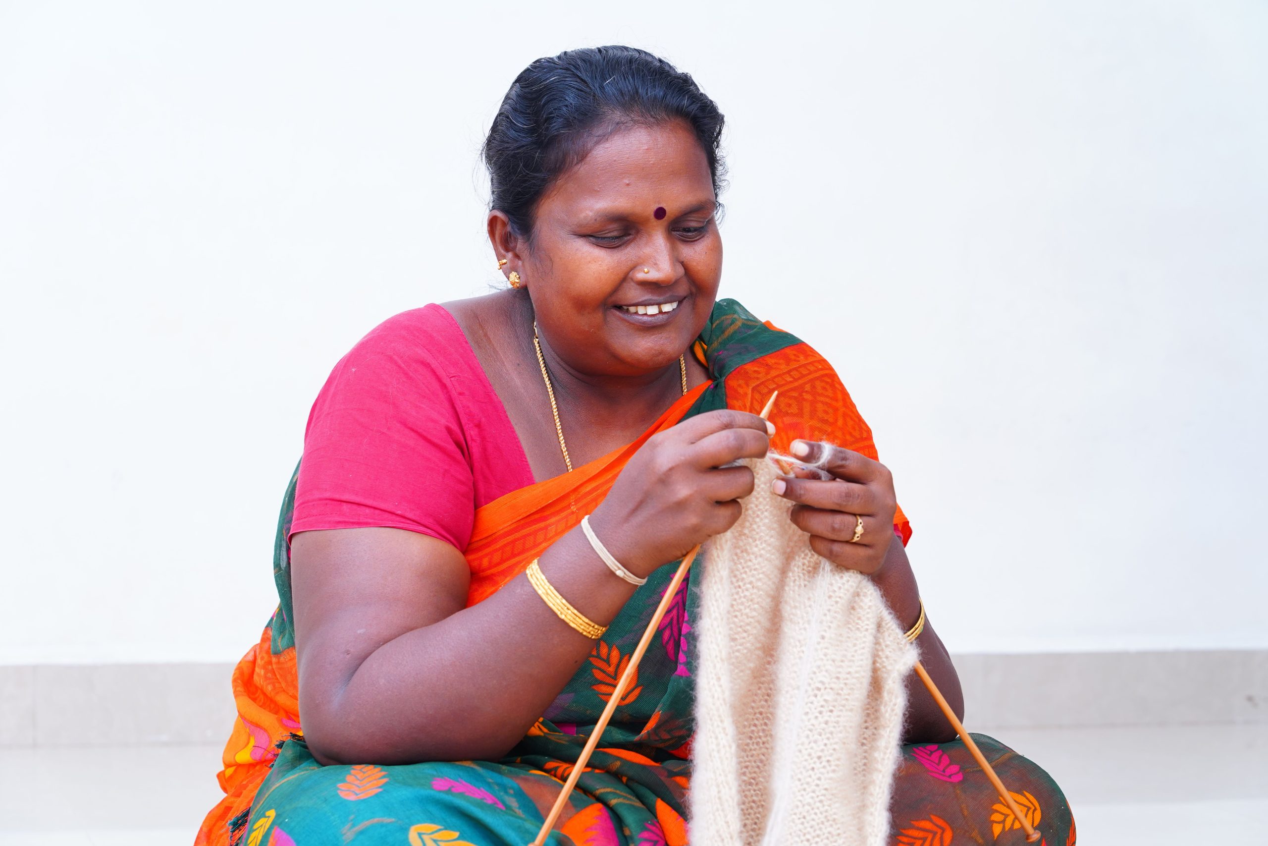 Woman knitting in colorful attire.