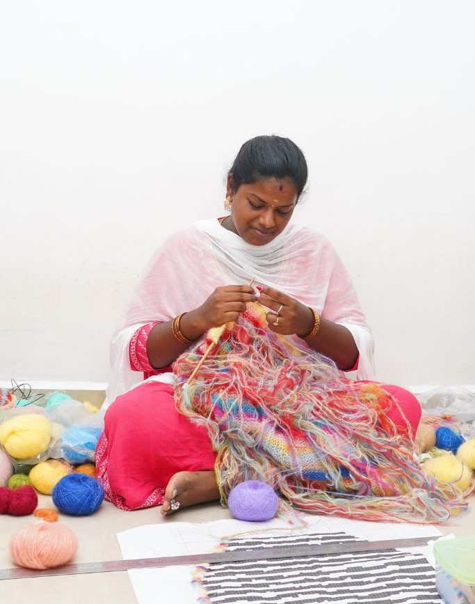 Person knitting surrounded by colorful yarn.