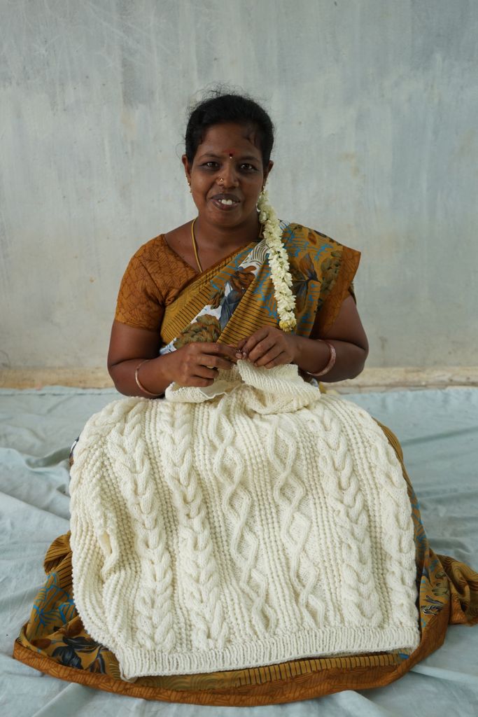 Woman knitting a white sweater.