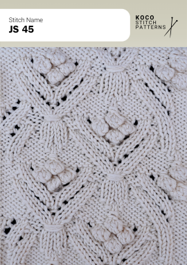 Raised bobble details and openwork lace form a soft, decorative handknit panel Close-up of the JS 45 handknit stitch pattern in white yarn, featuring raised bobble accents, openwork lace motifs, and textured knit stitches